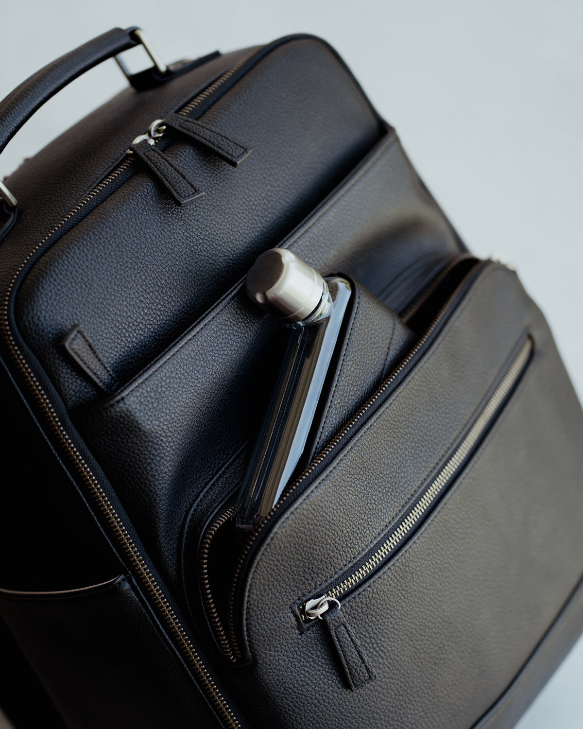 Memobottle water bottle in matching Lyra Camera backpack in black vegan leather