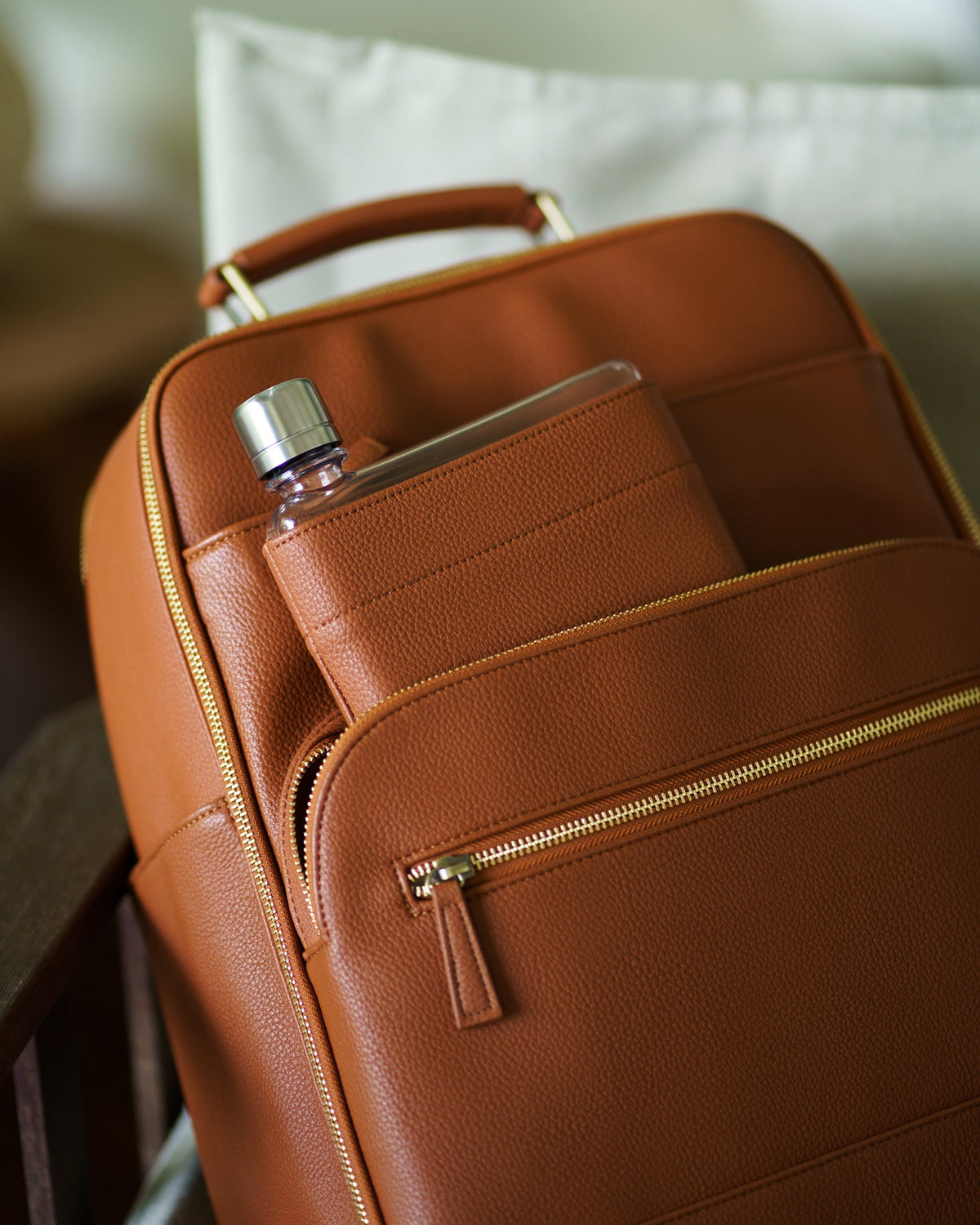 Memobottle water bottle with tan leather sleeve in matching Lyra Camera Backpack