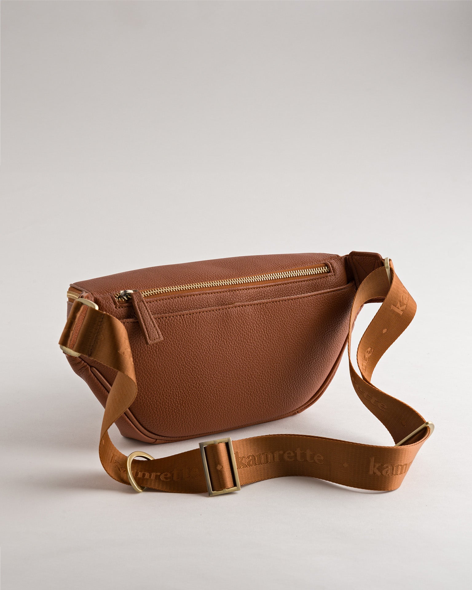 Back view of Versa Camera Crossbody in Tan with adjustable strap and secure storage
