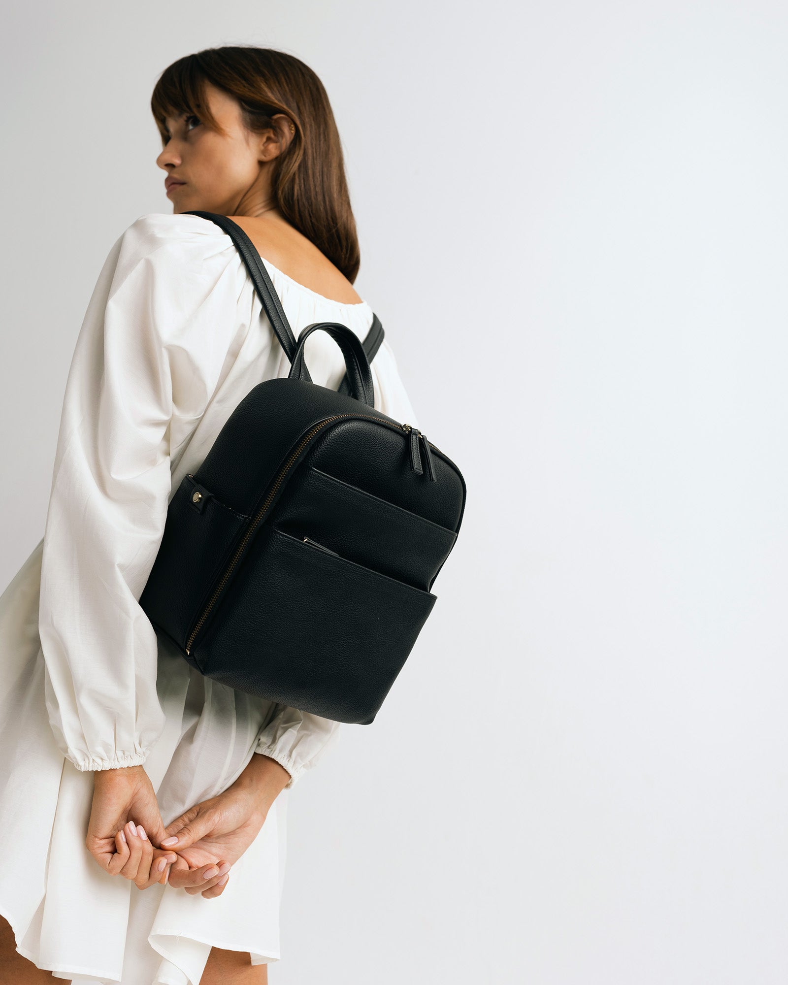 Woman photographer in photography studio wearing the Lyra backpack in black