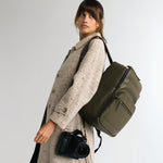 Woman photographer with a Canon camera and lens wearing the Lyra backpack in Olive