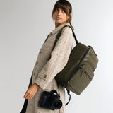 Woman photographer with a Canon camera and lens wearing the Lyra backpack in Olive