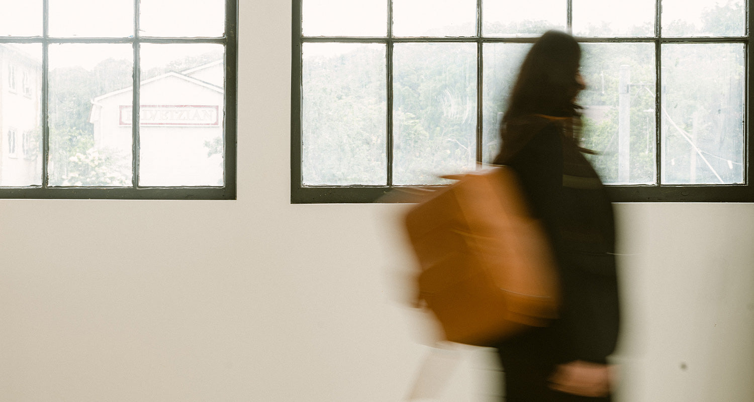 Blurry artistic photo of a wedding photographer carrying her camera bag in tan