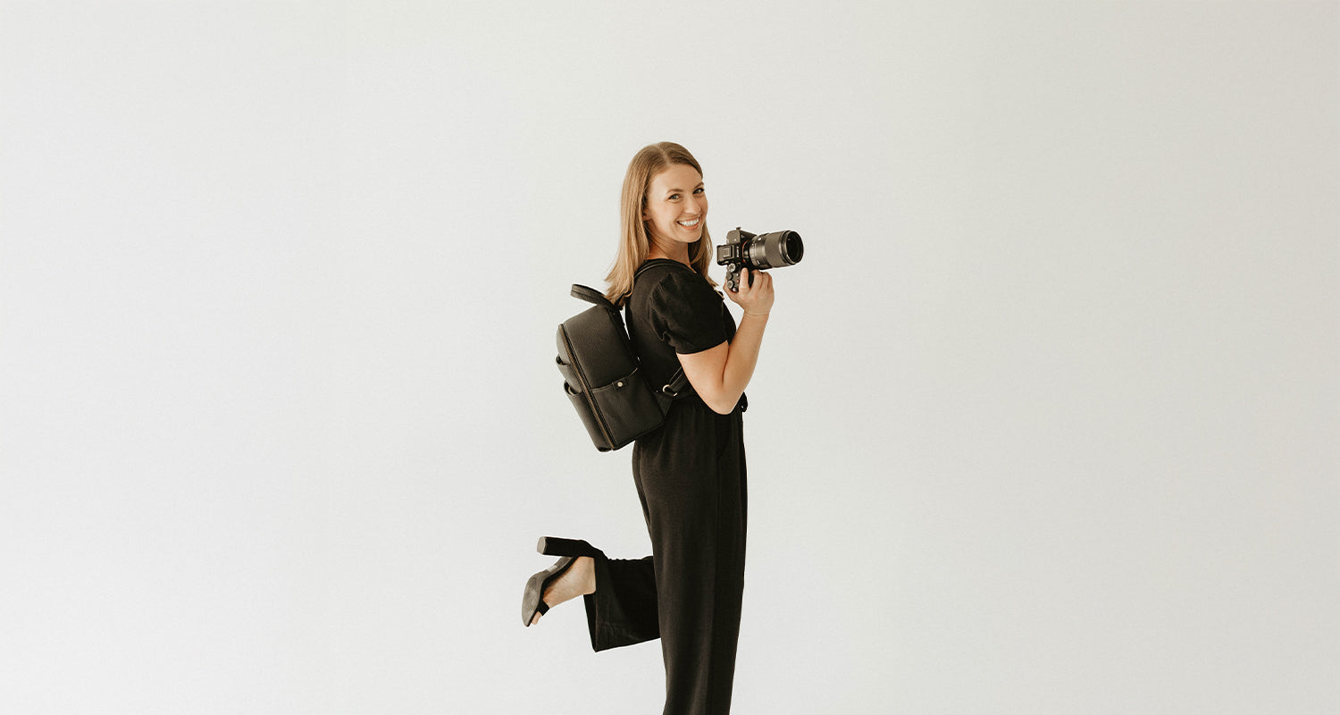 Woman photographer with black camera backpack and SLR camera