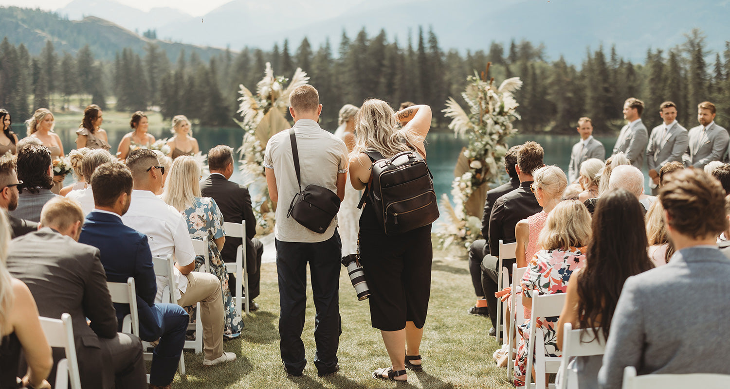 Wedding photographer wearing black camera bag photographing a wedding ceremony