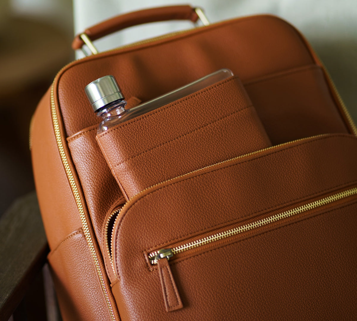 Memobottle water bottle with tan leather sleeve in matching Lyra Camera Backpack 