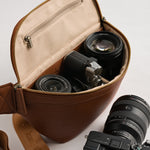 Fujifilm and Sony mirrorless camera and lenses inside padded Versa camera crossbody in Tan