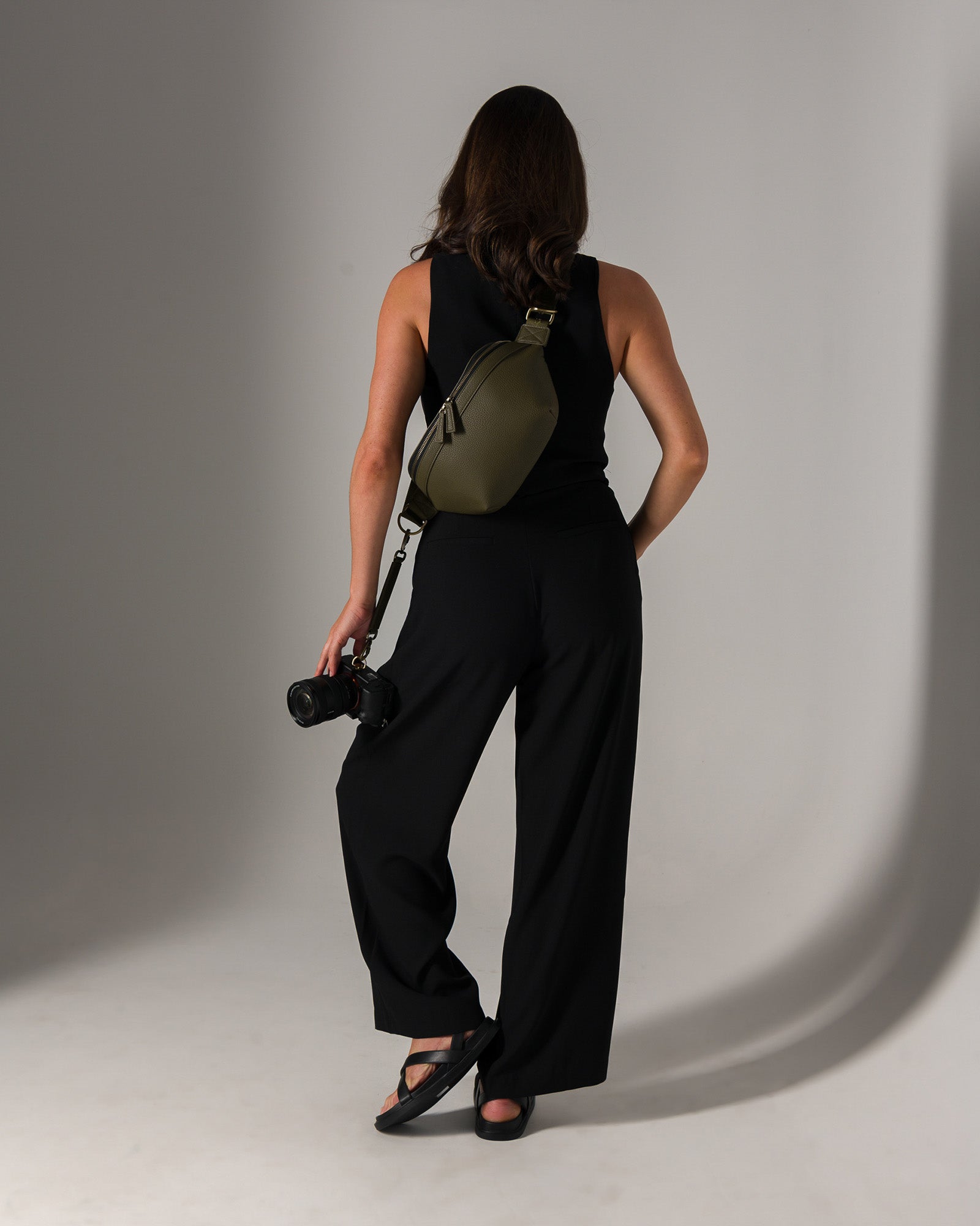 Photographer holding mirrorless camera attached with strap to Versa fanny pack