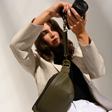 Woman photographer holding mirrorless camera attached to Versa Camera Bag using the camera strap