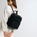 Woman photographer in photography studio wearing the Lyra backpack in black