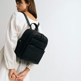 Woman photographer in photography studio wearing the Lyra backpack in black