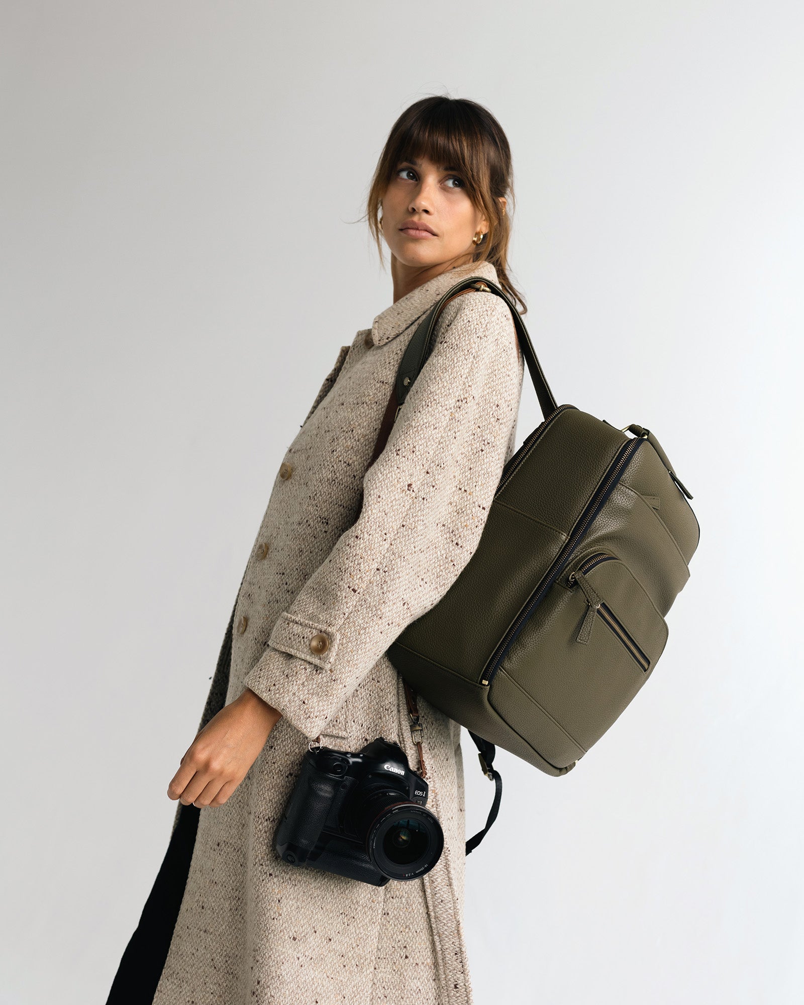 Woman photographer with a Canon camera and lens wearing the Lyra backpack in Olive
