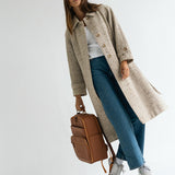 Woman photographer holding handle of Lyra Camera Backpack in stylish outfit