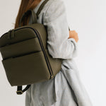 Woman photographer in stylish outfit wearing the Lyra camera backpack in Olive