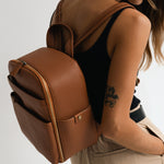 Woman photographer wearing Mina camera backpack in tan wearing minimalist outfit
