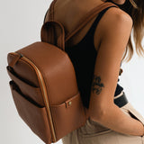 Woman photographer wearing Mina camera backpack in tan wearing minimalist outfit