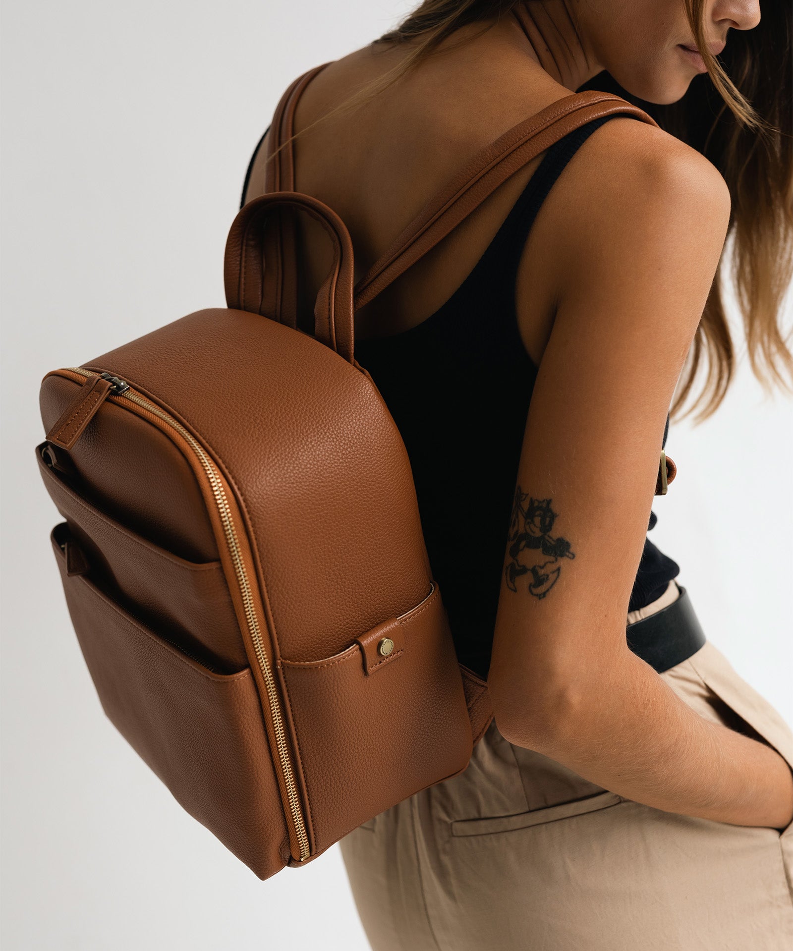 Woman photographer wearing Mina camera backpack in tan wearing minimalist outfit