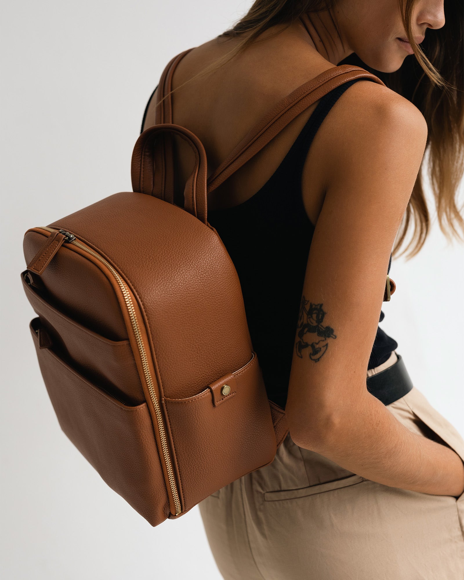 Woman photographer wearing Mina camera backpack in tan wearing minimalist outfit